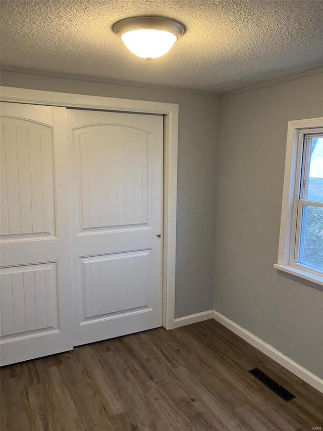 unfurnished bedroom with dark hardwood / wood-style flooring, a closet, and a textured ceiling