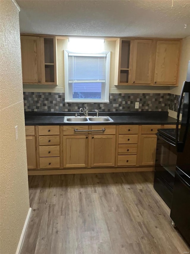 kitchen featuring backsplash, sink, light hardwood / wood-style flooring, and black appliances