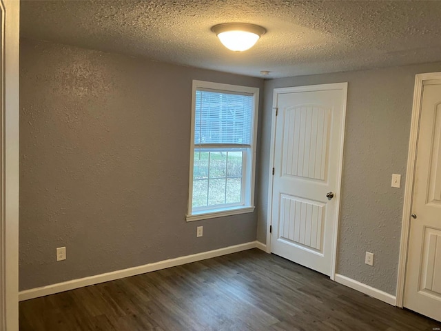 spare room with dark wood-type flooring and a textured ceiling