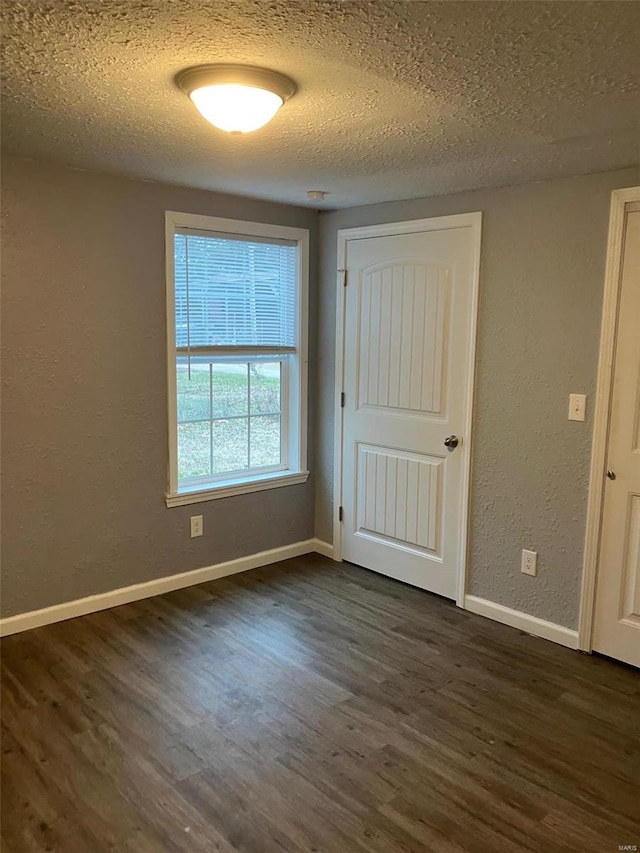 spare room with dark wood-type flooring and a textured ceiling