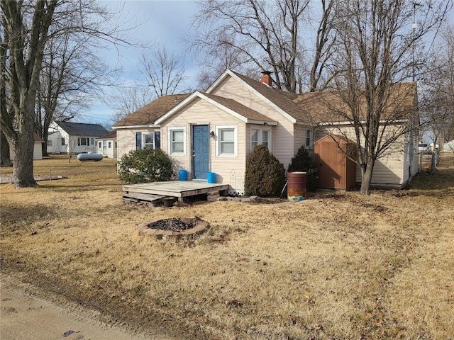 view of front of property with a storage unit, a fire pit, and a front yard