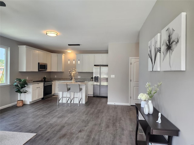 kitchen with stainless steel appliances, a kitchen island, white cabinets, and a kitchen breakfast bar