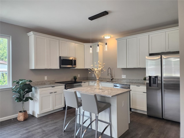 kitchen with stainless steel appliances, white cabinets, decorative light fixtures, light stone counters, and dark hardwood / wood-style floors