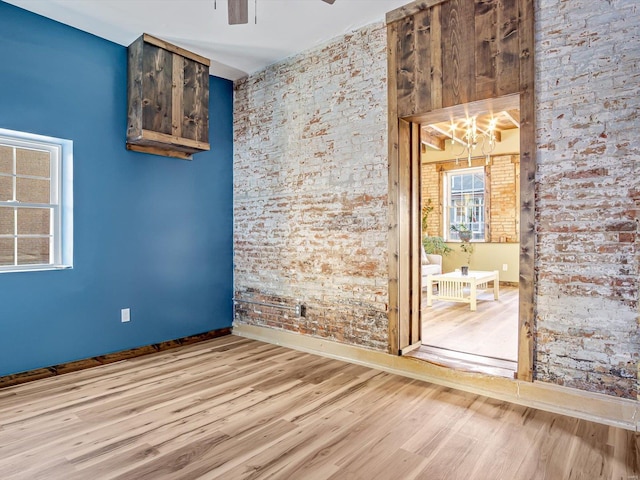 spare room featuring ceiling fan with notable chandelier and light wood-type flooring