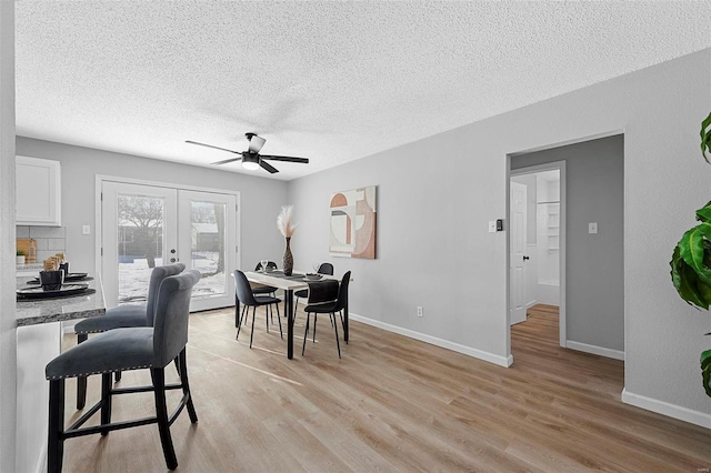 dining room with ceiling fan, a textured ceiling, light hardwood / wood-style flooring, and french doors