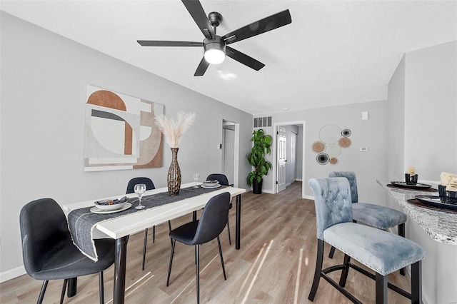 dining space with a textured ceiling, ceiling fan, and light hardwood / wood-style floors