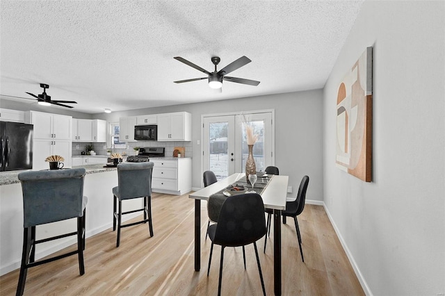 dining area with french doors, a textured ceiling, and light hardwood / wood-style floors