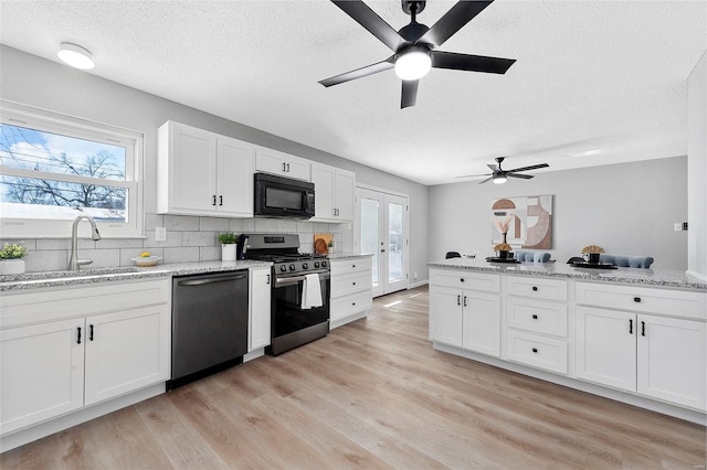 kitchen featuring a textured ceiling, white cabinetry, decorative backsplash, and black appliances