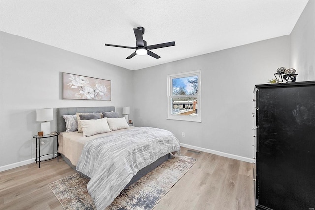 bedroom featuring ceiling fan, a textured ceiling, and light wood-type flooring