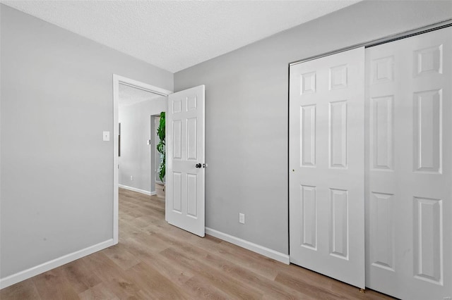 unfurnished bedroom featuring a textured ceiling, a closet, and light wood-type flooring