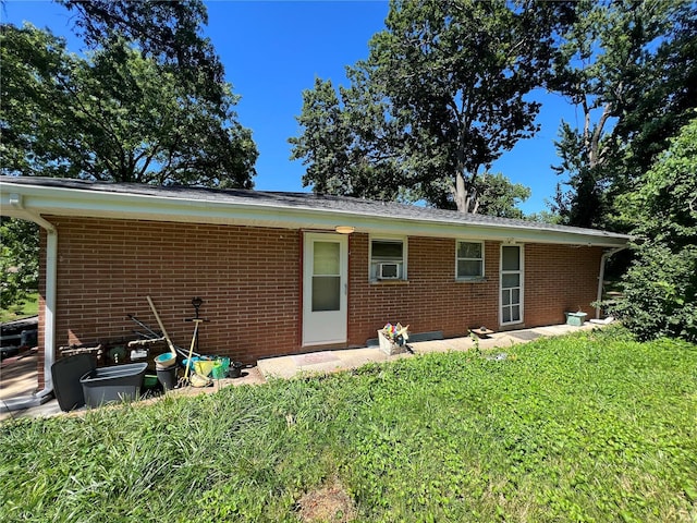 rear view of property featuring a lawn and cooling unit