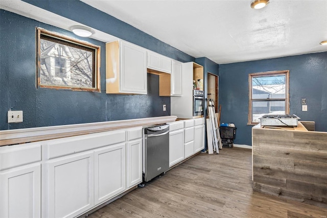 kitchen featuring stainless steel oven, light hardwood / wood-style floors, and white cabinets