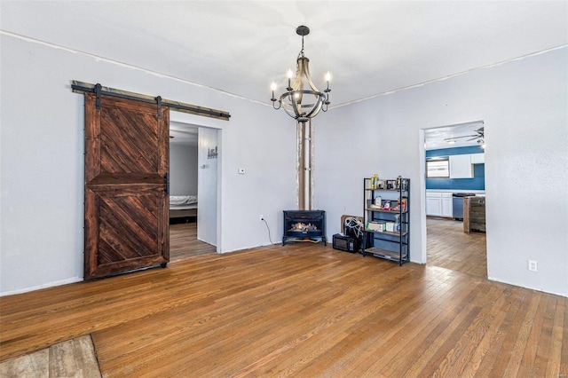 spare room with hardwood / wood-style flooring, a barn door, and ceiling fan with notable chandelier