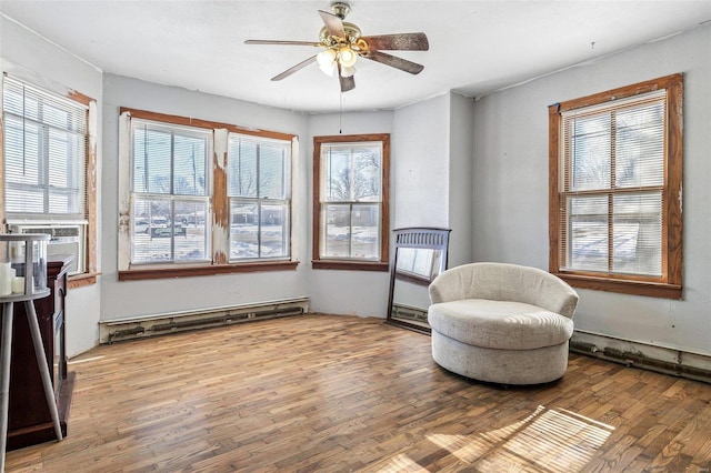 living area with hardwood / wood-style flooring, cooling unit, a baseboard heating unit, and ceiling fan