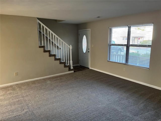 foyer entrance featuring dark colored carpet