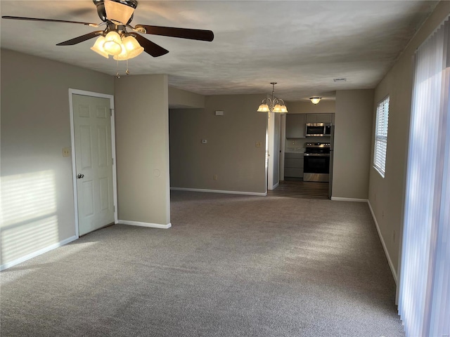 carpeted spare room with ceiling fan with notable chandelier