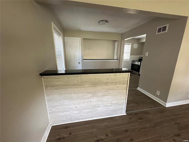 kitchen with dark wood-type flooring, electric stove, and a wealth of natural light