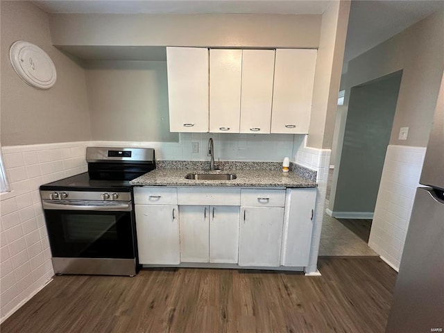 kitchen with dark hardwood / wood-style floors, dark stone countertops, sink, stainless steel electric stove, and white cabinets