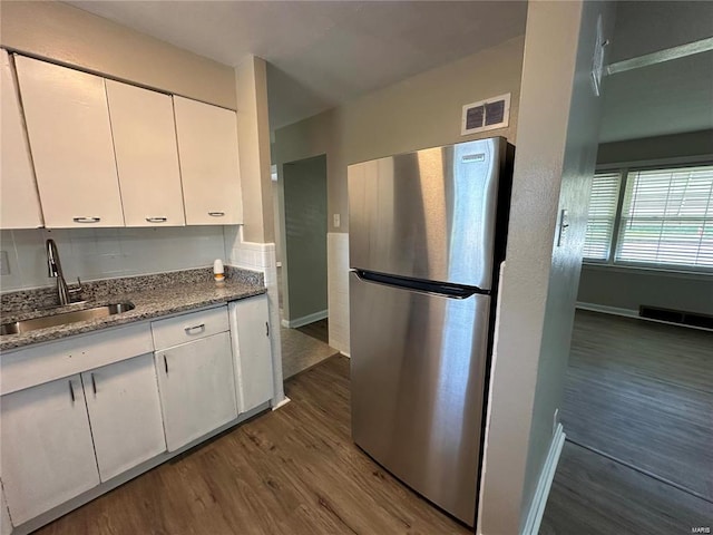 kitchen with stainless steel fridge, dark wood-type flooring, stone counters, white cabinets, and sink