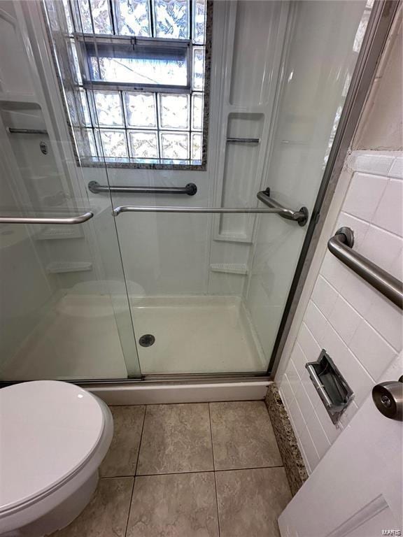 bathroom with toilet, walk in shower, and tile patterned flooring