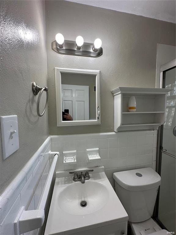 bathroom with toilet, vanity, tile walls, and backsplash