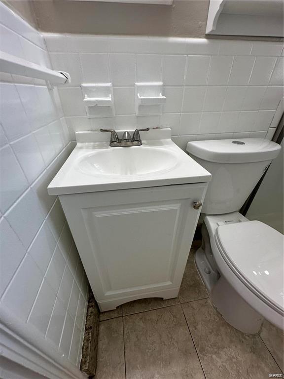 bathroom featuring tile patterned floors, tile walls, toilet, and vanity