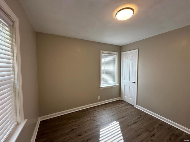 spare room with a healthy amount of sunlight and dark wood-type flooring