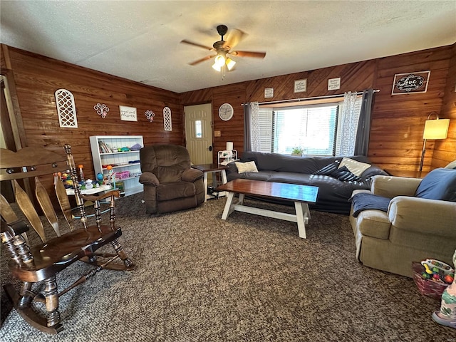 carpeted living room featuring ceiling fan, wood walls, and a textured ceiling