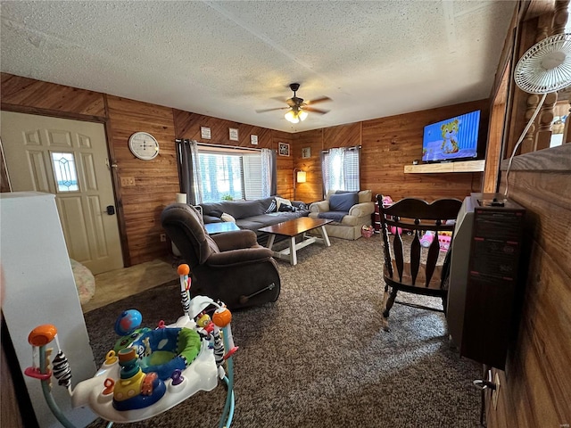 living room with ceiling fan, carpet, wood walls, and a textured ceiling