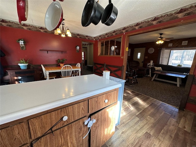 kitchen with a textured ceiling, dark hardwood / wood-style flooring, and ceiling fan with notable chandelier