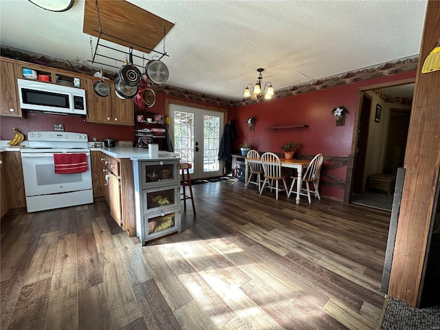 kitchen featuring an inviting chandelier, decorative light fixtures, white appliances, dark wood-type flooring, and a textured ceiling