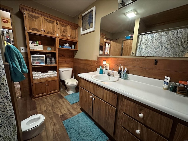 bathroom with toilet, wooden walls, hardwood / wood-style flooring, and vanity