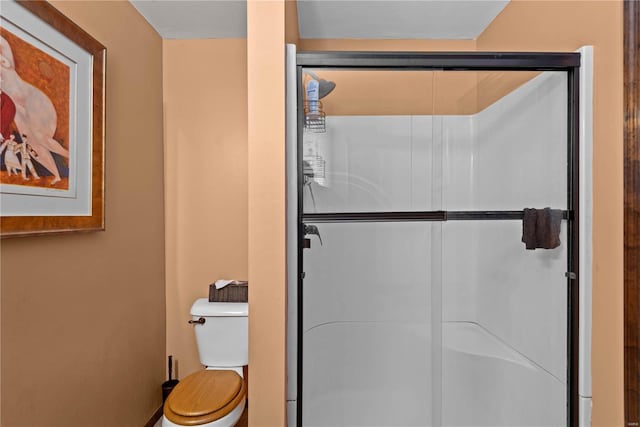 bathroom featuring toilet and a shower with shower door