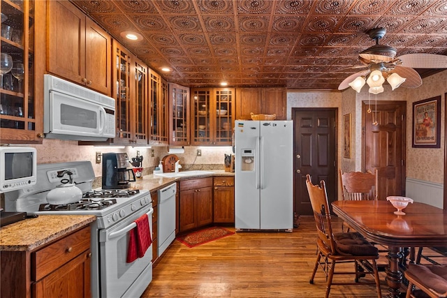 kitchen with ceiling fan, white appliances, light wood-type flooring, light stone counters, and sink