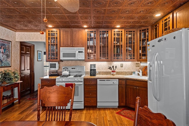 kitchen with hanging light fixtures, sink, white appliances, and light hardwood / wood-style flooring