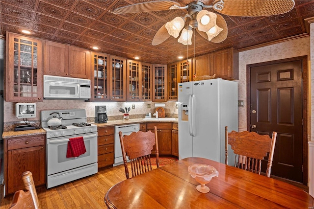 kitchen with light stone countertops, white appliances, sink, light wood-type flooring, and ceiling fan