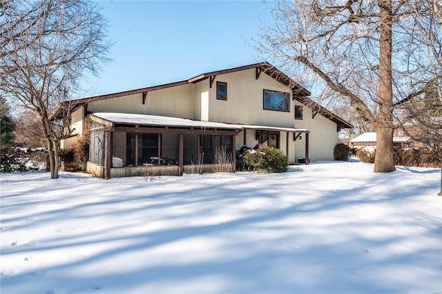 snow covered back of property with a sunroom