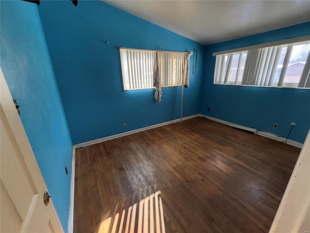 spare room featuring lofted ceiling and dark hardwood / wood-style floors