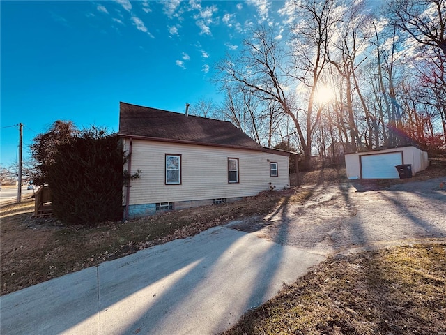 view of property exterior with a garage, driveway, and an outdoor structure