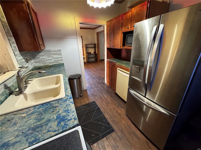 kitchen featuring dark wood finished floors, stainless steel refrigerator with ice dispenser, decorative backsplash, a sink, and dishwasher