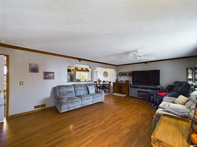 living room with a textured ceiling, ceiling fan, crown molding, and hardwood / wood-style floors