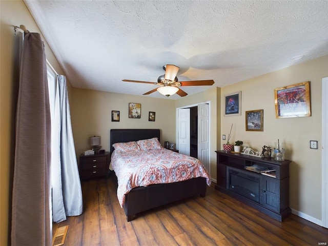 bedroom with ceiling fan, a textured ceiling, and dark hardwood / wood-style floors