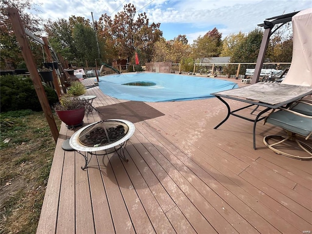 view of pool with a wooden deck and a fire pit