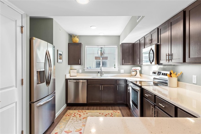 kitchen with light wood-type flooring, appliances with stainless steel finishes, dark brown cabinets, and sink