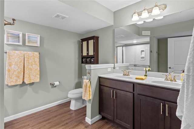 bathroom featuring a shower with shower door, hardwood / wood-style flooring, vanity, and toilet