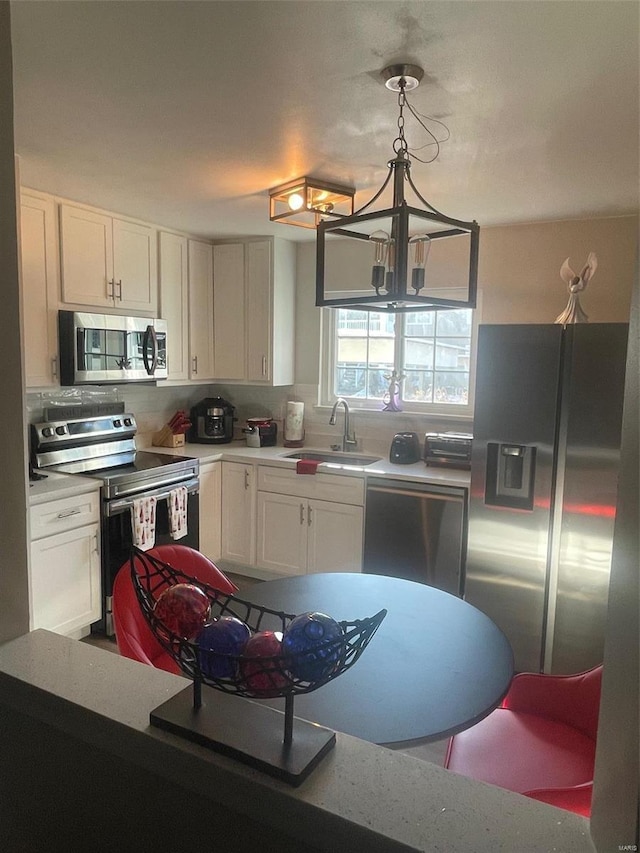 kitchen with pendant lighting, sink, white cabinets, and appliances with stainless steel finishes