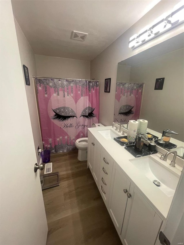 bathroom featuring hardwood / wood-style floors, toilet, vanity, and walk in shower