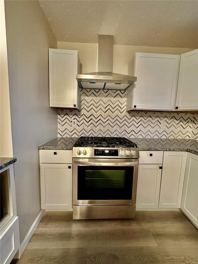 kitchen with wall chimney range hood, gas stove, white cabinets, and stone counters