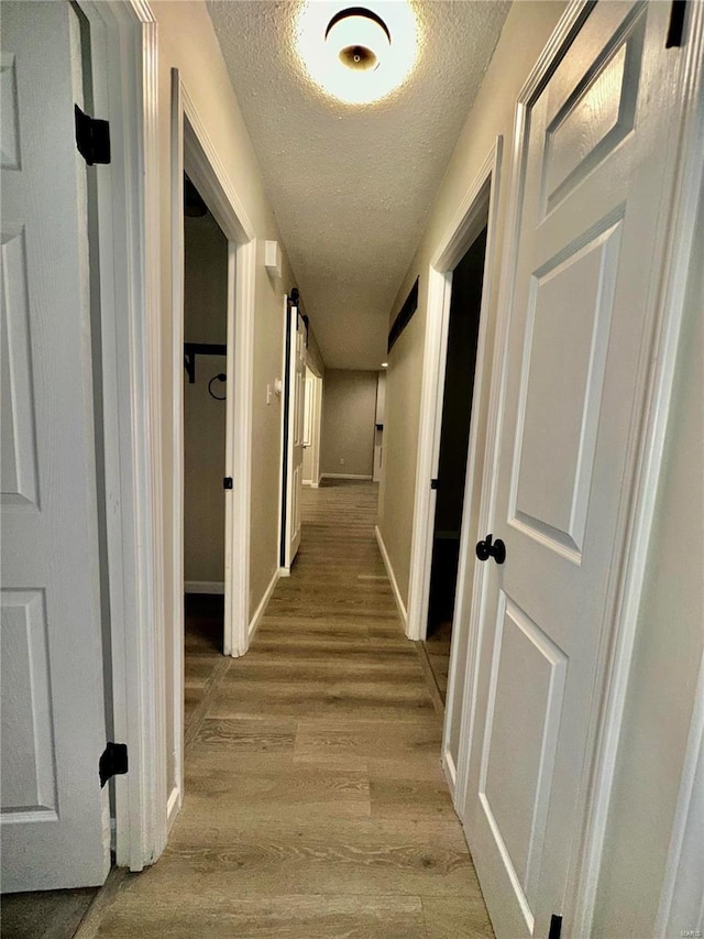 corridor with light hardwood / wood-style flooring and a textured ceiling