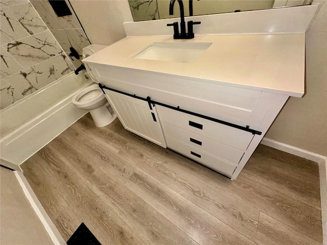 full bathroom featuring vanity, tiled shower / bath, wood-type flooring, and toilet